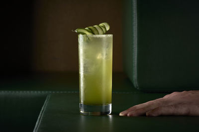 Green lemonade cocktail with cucumber on green sofa