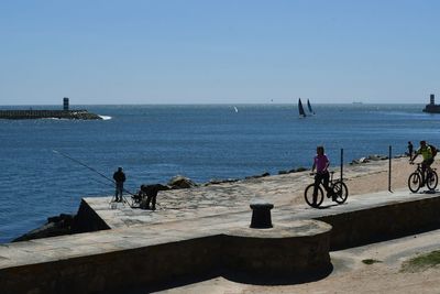 People by sea against clear sky