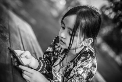 Close-up of girl using mobile phone on table