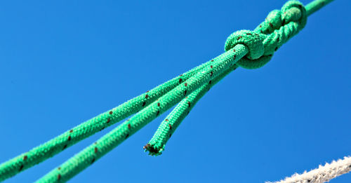 Low angle view of rope tied up against blue sky