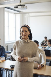 Portrait of female professor standing in classroom