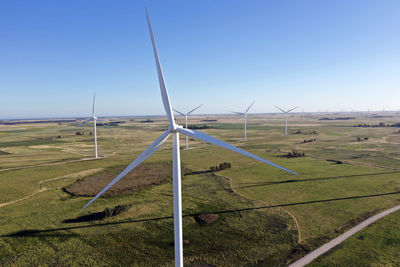 Windmills on field against clear sky