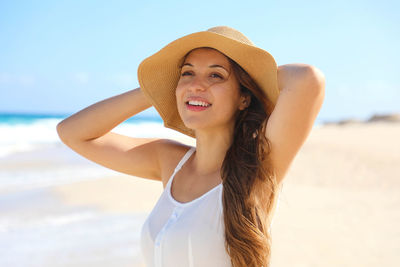 Smiling woman looking away while standing at beach