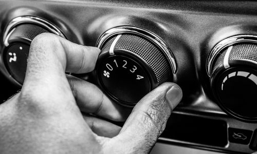 Cropped hand adjusting air conditioner button in car