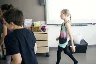 School children walking against whiteboard in classroom