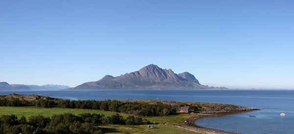 Scenic view of sea and mountains against clear blue sky