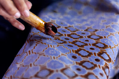 Cropped hand of person cutting tile