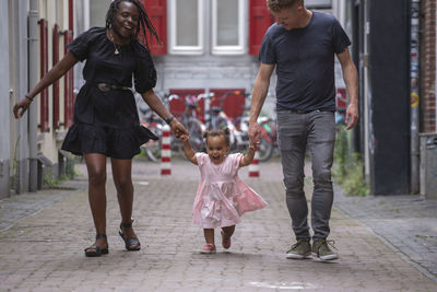 A mixed race family walking through the city with their young daughter