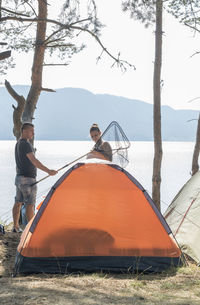 Friends by tent at lakeshore