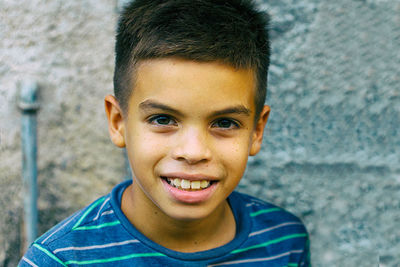 Close-up portrait of smiling boy against wall