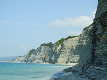 Scenic view of sea by cliff against sky