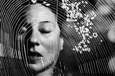 Close-up of woman with closed eyes seen through spider web