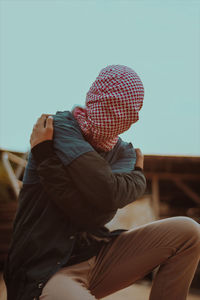 Rear view of man sitting by hat