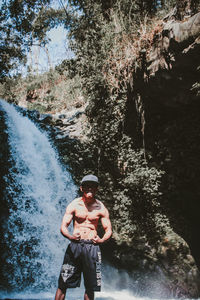 Full length of man standing on rock against waterfall