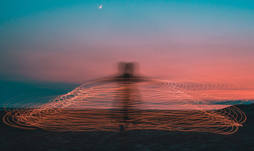 Digital composite image of man standing by sea against sky during sunset