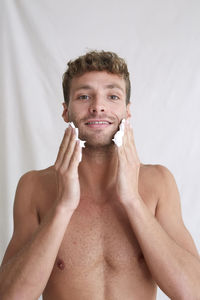 Portrait of shirtless man standing against white background