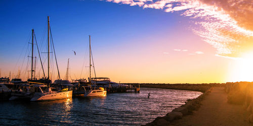 Sailboats in sea at sunset