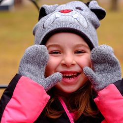 Close-up portrait of smiling girl wearing knit hat and gloves