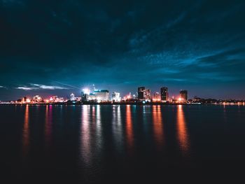 City skyline by calm sea at night