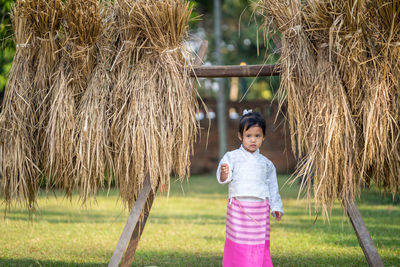 Girl standing on grass by haystack at park