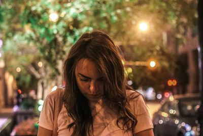 Portrait of woman looking at illuminated city at night