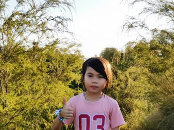 Portrait of girl standing against trees