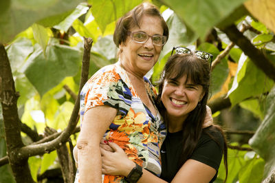 Portrait of young woman embracing her mother by plants