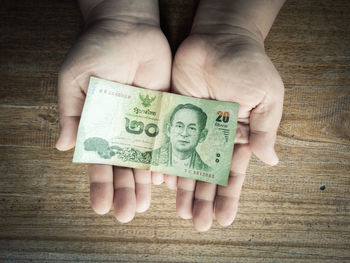 Cropped hands holding paper currency over table