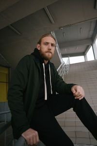 Portrait of young man sitting by steps