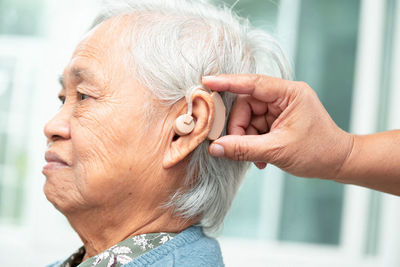 Asian senior woman patient wearing a hearing aid for treating hearing loss problem.