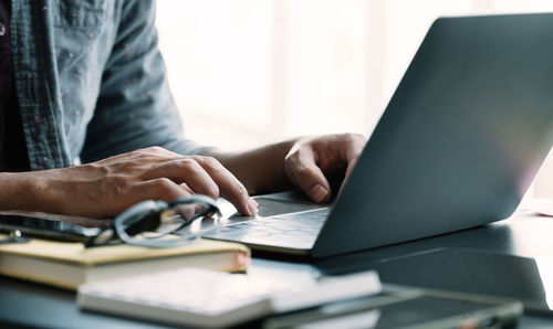 Midsection of man using laptop on table