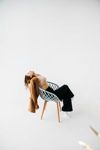 Full length of woman sitting over white background