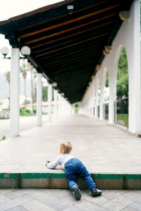 Rear view of boy sitting on bridge