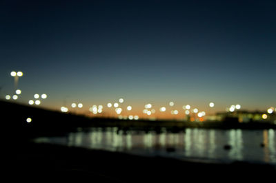 Defocused image of illuminated city against sky at night