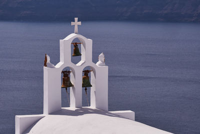 Small church with its three bells tower in imerovigli village - santorini island, greece