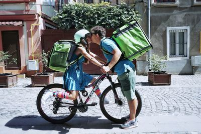 Couple with bicycle kissing on street in city