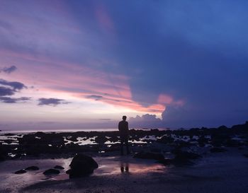 Silhouette man standing on beach against sky during sunset