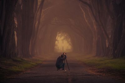 Rear view of man photographing on road