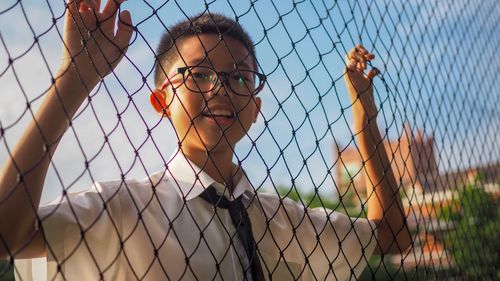 Portrait of boy seen through chainlink fence
