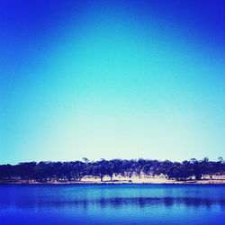 Scenic view of calm lake against clear blue sky