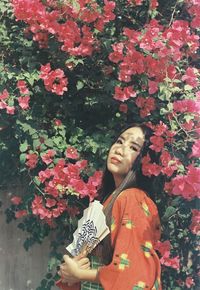 Portrait of smiling young woman holding flowering plants