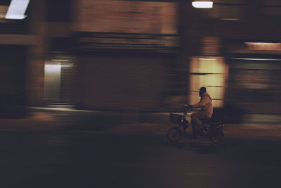 High angle view of man riding bicycle on street by building at night