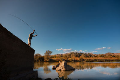 Reflection of man in lake against sky