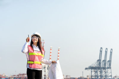 Portrait of smiling young woman standing against sky