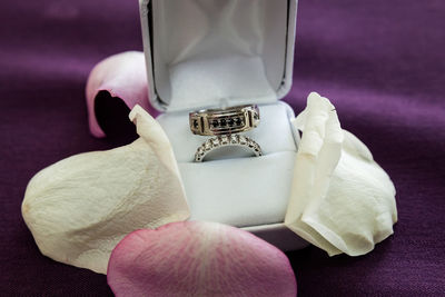 High angle view of wedding rings in jewelry box amidst petals