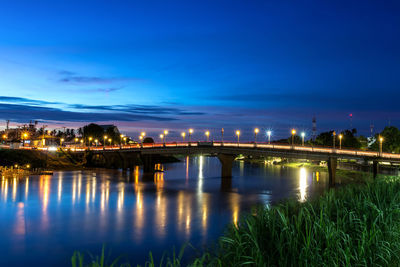 Illuminated bridge over river against sky at night