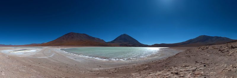 Panoramic view of sea and mountains against clear blue sky