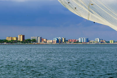 Sea by buildings against sky in city