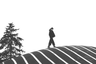 Woman walking on roof against clear sky