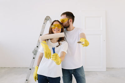 A young couple in love have moved into a new house and are making repairs painting white walls